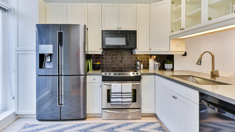 a kitchen with white cabinets and stainless steel appliances.