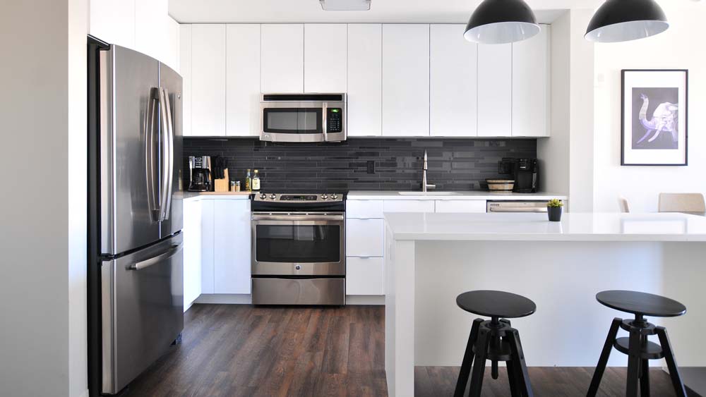 a kitchen with a stove, refrigerator, and stools.