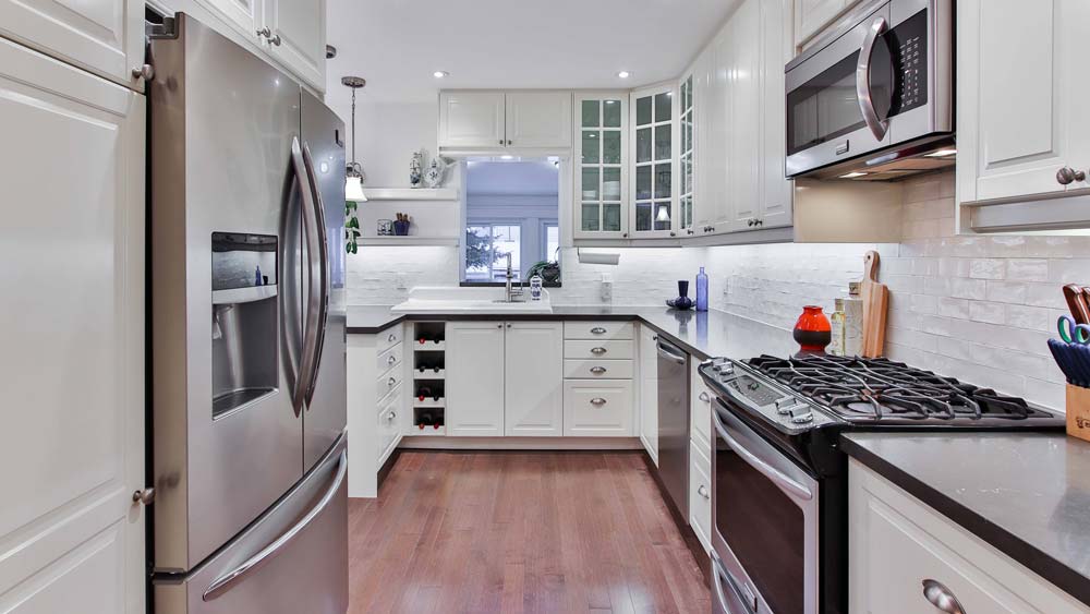 a kitchen with white cabinets and stainless steel appliances.