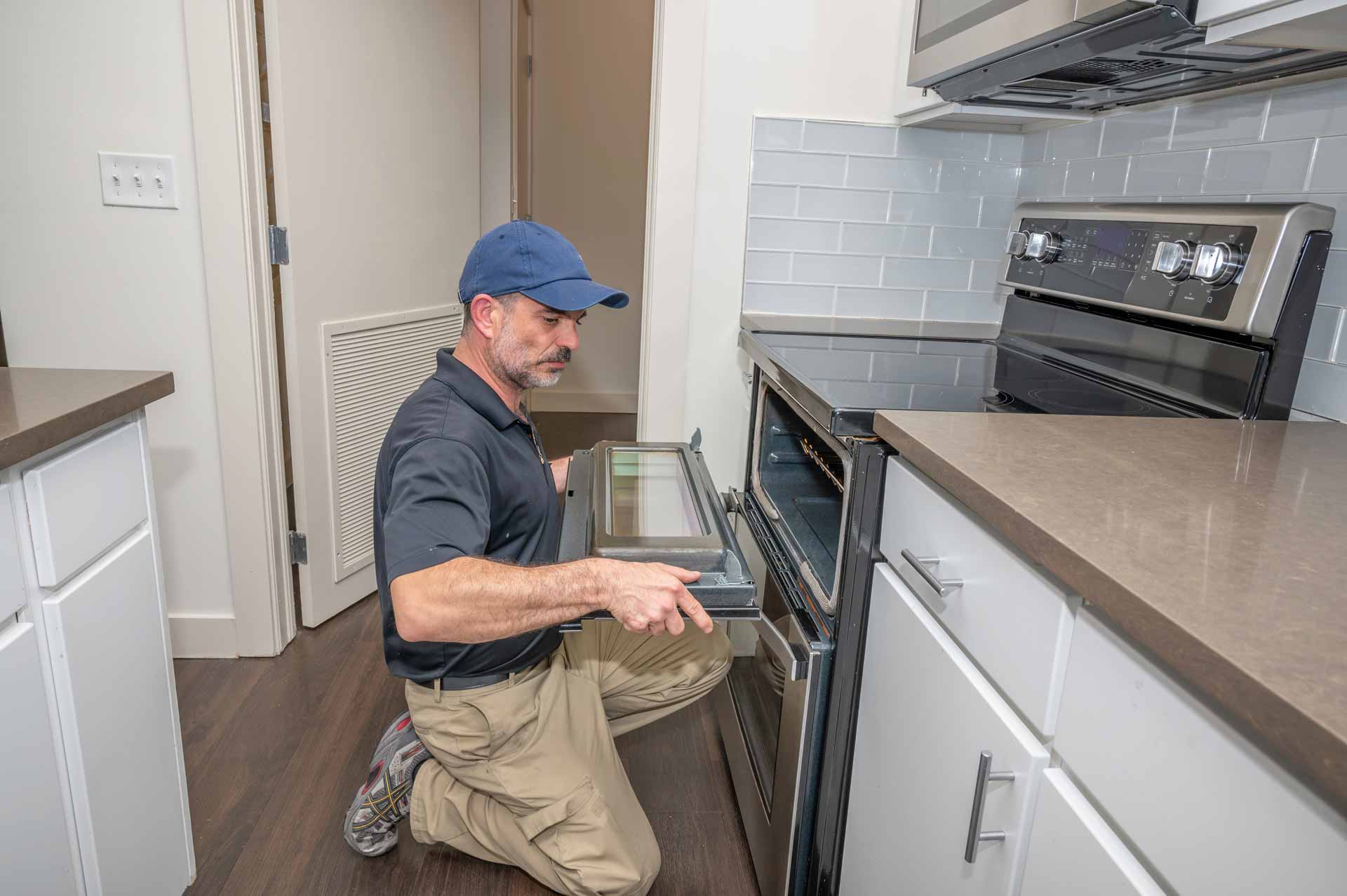 a man kneeling down in front of an oven.